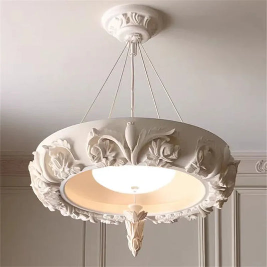 Artistic carved plaster chandelier with white LED lights.